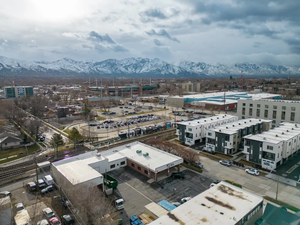 An aerial view of commercial buildings in the Salt Lake Valley with snowy mountains behind